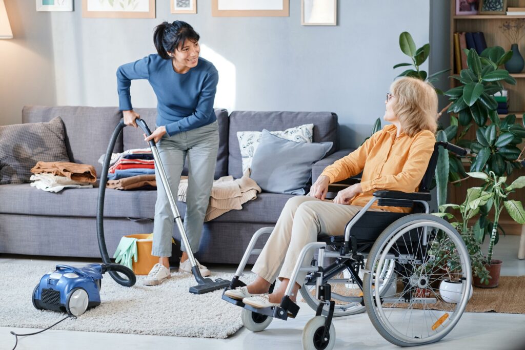 person vacuuming and talking to lady in wheelchair