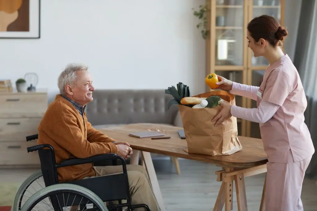Support Worker delivering Food for Senior Wheelchair person with disability