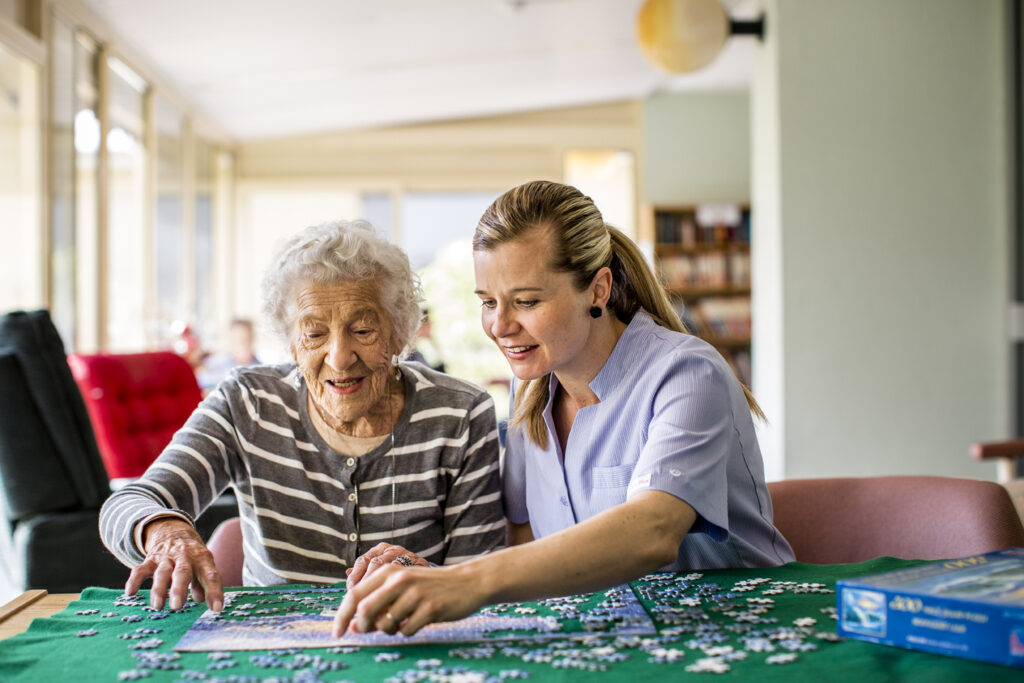 woman and elderly lady doing a jigsaw puzzle